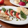 Caprese Appetizer: Thickly sliced buffalo mozzarella topped with roma tomatoes, fresh basil, kalamata olives, & homemade pesto